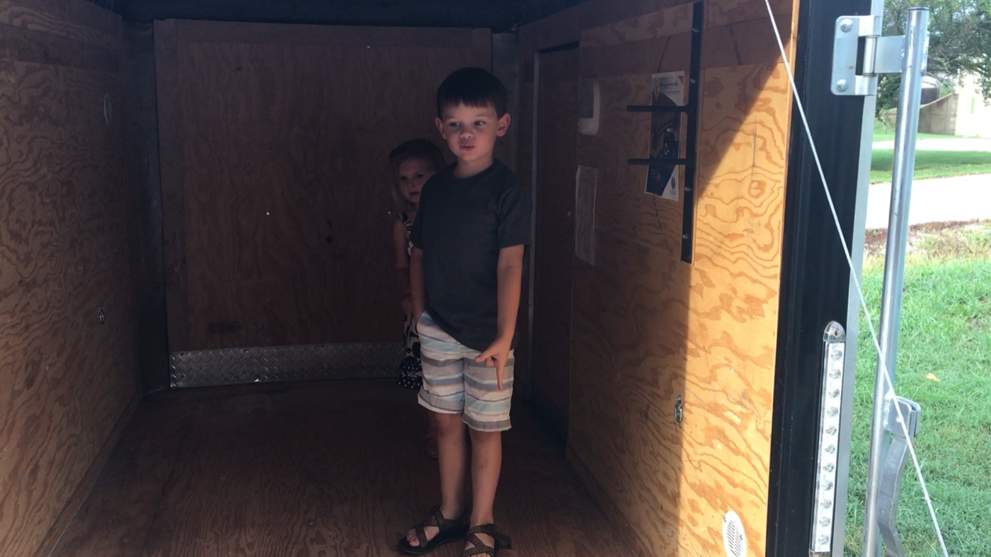 Kids standing in empty 5&times;8 trailer for scale