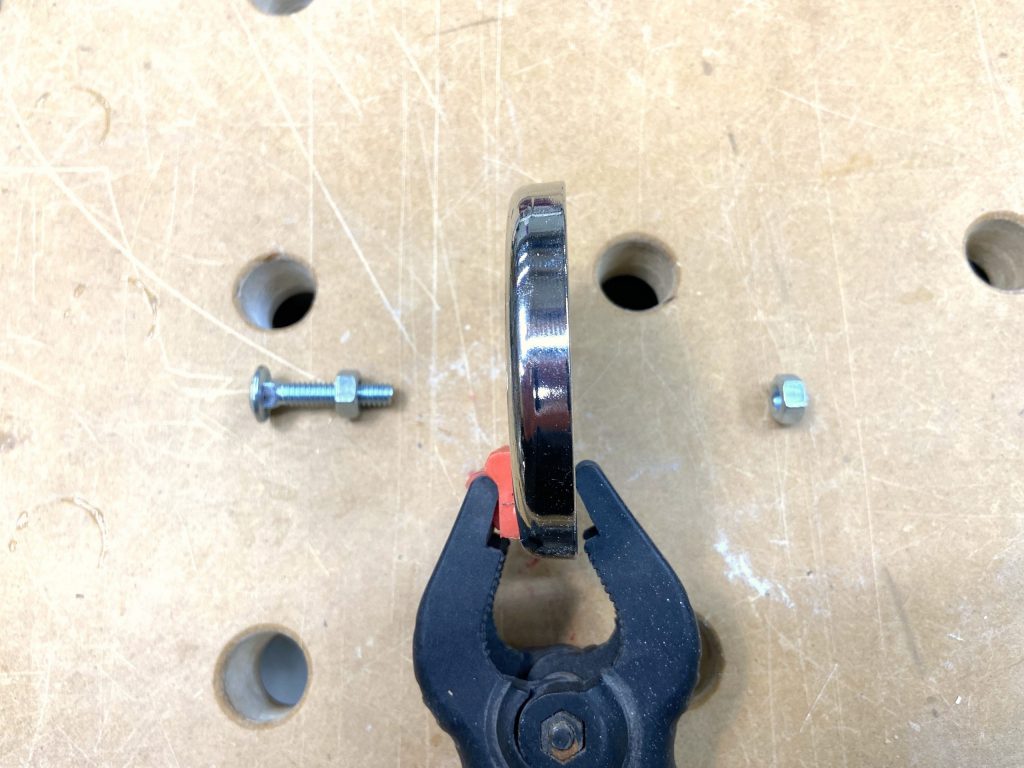 Carriage bolt, magnet, and nuts laid out